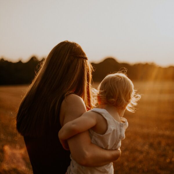 Mother holding toddler looking into the sunset